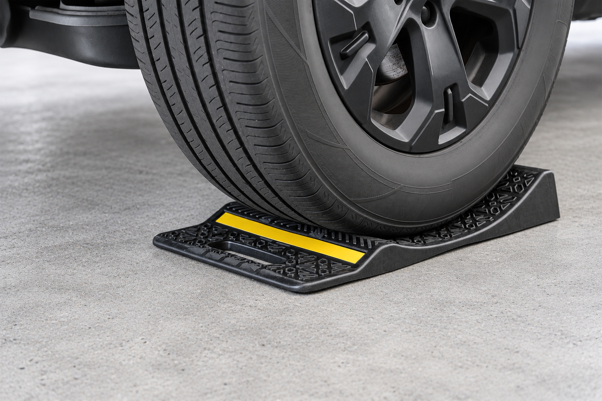 Angled tire close-up showing the textured surface, carry handle and yellow reflective strip of a single-sided parking mat