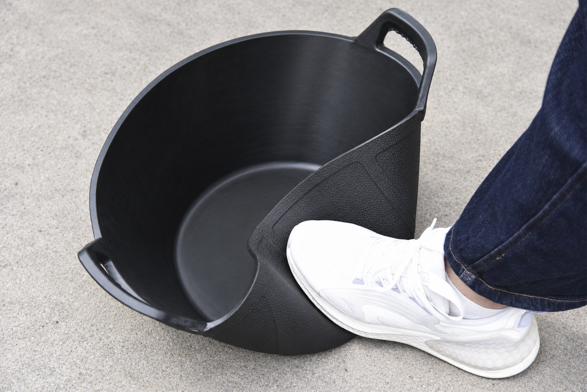 Sidewall of a black rubber feed pan flexing inward under pressure from a shoe