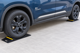 Vehicle front and rear wheels positioned on heavy-duty double-sided parking mats