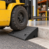 Forklift wheel on a black curb ramp at a warehouse entrance